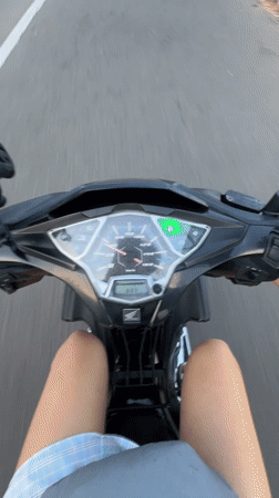 Woman rides scooter through Mui Ne wearing white helmet