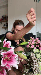 Woman arranges fresh flowers on living room floor