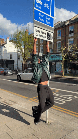 Man hangs from bus lane sign in London street
