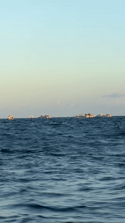Golden hour over the Bali coast, boats on the horizon