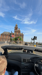 BMW convertible drives through Great Yarmouth on sunny afternoon