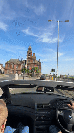 BMW convertible drives through Great Yarmouth on sunny afternoon