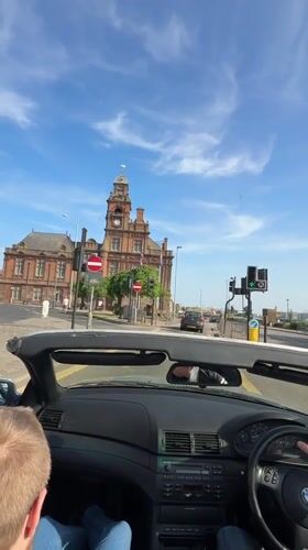 BMW convertible drives through Great Yarmouth on sunny afternoon