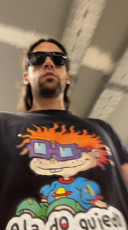 Long-haired man in cartoon shirt walks Buenos Aires tunnel