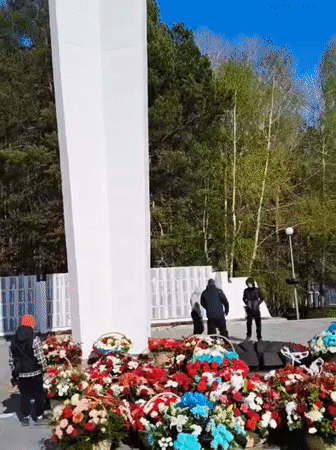 Memorial site displays colorful flower arrangements in circular pattern
