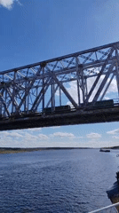 Train crosses steel bridge over river near Tarkanovo, Russia
