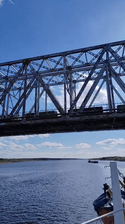 Train crosses steel bridge over river near Tarkanovo, Russia