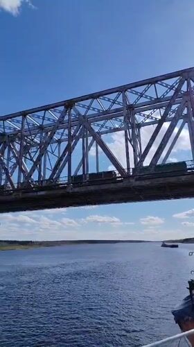 Train crosses steel bridge over river near Tarkanovo, Russia