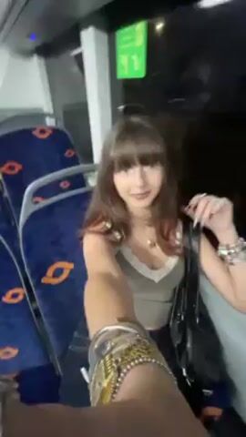 The video shows the interior of a bus at night. A young woman with brown hair and bangs is seen briefly in the first shot. The bus appears empty, with rows of blue and orange patterned seats. The camera pans toward the rear of the bus showing gray seats and yellow handrails. The lighting inside is bright, and the windows show dark outside.