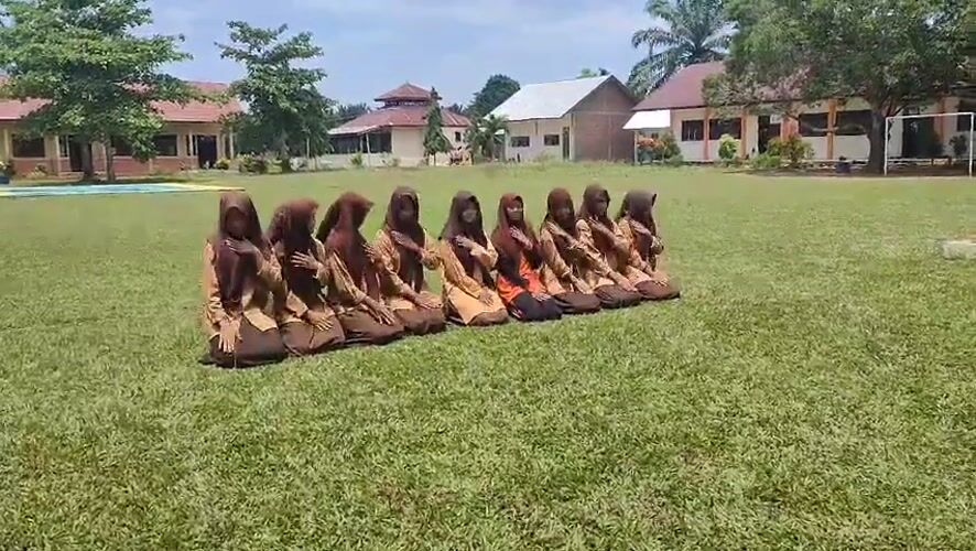 Students perform synchronized dance in uniforms on Indonesian field