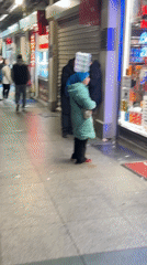 Woman carries water bottles on head outside Beyoğlu shop