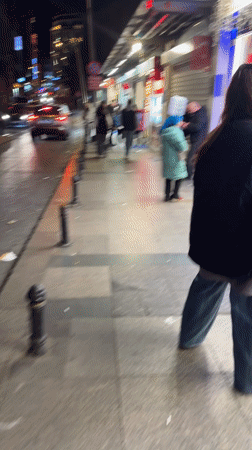 Woman carries water bottles on head outside Beyoğlu shop