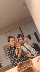 Two women take mirror selfie in Singkawang indoor setting