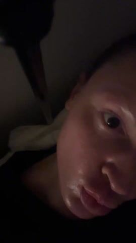 Here's a description of the video:
A person with light skin and short hair speaks to the camera in a dim room. The person makes a "thumbs up" gesture with their hand. A black post is visible near the ceiling. The background wall is gray.
