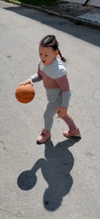 Girl practices basketball on cracked asphalt court