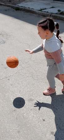 Girl practices basketball on cracked asphalt court