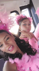 Women in pink feathered costumes pose in vehicle in Porlamar
