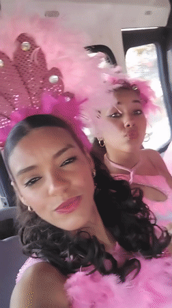Women in pink feathered costumes pose in vehicle in Porlamar