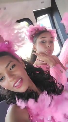 Women in pink feathered costumes pose in vehicle in Porlamar