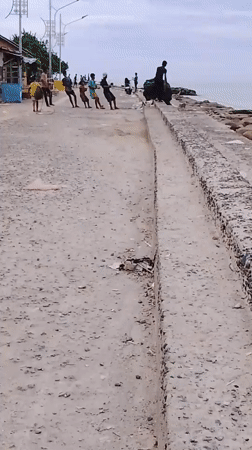 Families gather at polluted Lhokseumawe seawall watching fishing boats