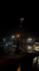 Nighttime dockyard activity captured with illuminated crane and ships