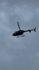 Black helicopter in low flight over Estepona's cloudy skies