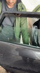Person tends to car on rainy afternoon in Lovech