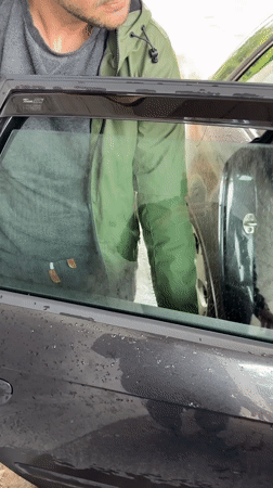 Person tends to car on rainy afternoon in Lovech