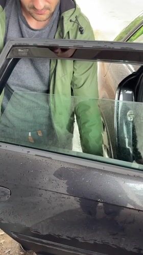Person tends to car on rainy afternoon in Lovech