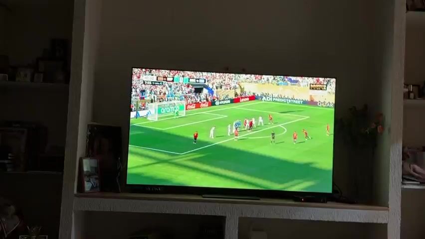 The video shows a soccer game from a broadcast. The score is 0-0 between ESP and ARG at 90 minutes with 7 minutes of added time. A free kick is being taken by the team in red. A player in red kicks the ball toward the goal. A player in white attempts to head the ball. The ball goes to the goalkeeper who is in green and white. A player in red is celebrating. A player in white has his hands over his face. The referee is on the field. The crowd is visible in the background. There are advertisements around the field.