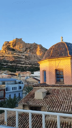 Alicante's hilltop castle glows at sunset from a rooftop view