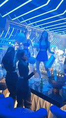 Five women dance on nightclub bar in coordinated outfits