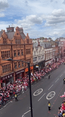 Large red-white clad crowd gathers along London street