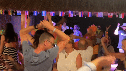 Dancing and celebrating under a flag-lined thatched roof at night