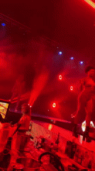 Red-clad performers light up a dimly lit club stage