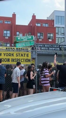 Crowd clusters behind chain-link fence near New York inspection site