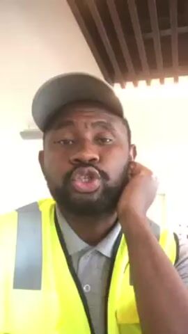 A man with a dark beard and wearing a gray cap and yellow reflective vest is looking at the camera and speaking. He has his right hand raised with his fingers touching his ear. He is indoors under a light fixture and a ceiling with brown slats. He first says, "Be good, good, good, be good." Then he says, "Be a good person, be a good person. Help if..." The video ends mid-sentence.