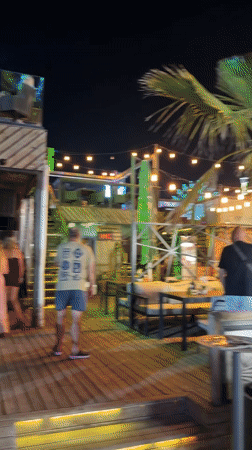 Summer evening foot traffic along Nesebar's palm-lined pedestrian strip.