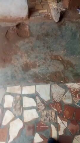 The video shows a close-up view of what appears to be a tiled floor. The tiles are irregular in shape and color, with some appearing to be broken or chipped. The lighting is dim, and the focus shifts throughout the video. There are no people or objects clearly visible in the frame. The overall impression is of an aged or weathered surface.