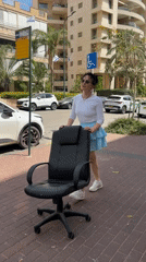 Woman pushes office chair down sidewalk in Netanya