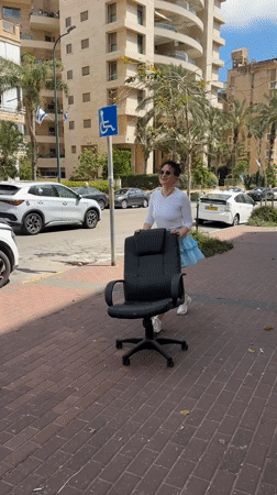 Woman pushes office chair down sidewalk in Netanya