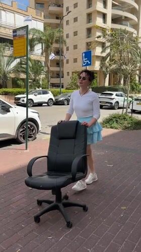 Woman pushes office chair down sidewalk in Netanya