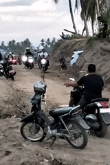 Motorcycles and crowds gather along riverbank in Kapa, Indonesia