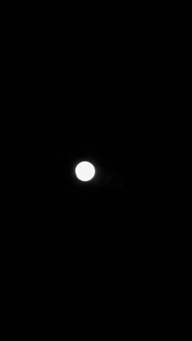 The video shows a full moon in a dark night sky. The moon is circular and has visible craters and markings on its surface. The background is completely black, with no other visible objects or light sources.