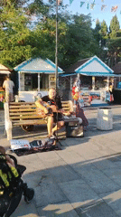 Street musician plays acoustic guitar at an outdoor public spot