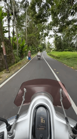 Motorcyclist rides silver Yamaha scooter on Baturiti road