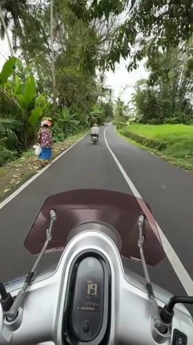 Motorcyclist rides silver Yamaha scooter on Baturiti road