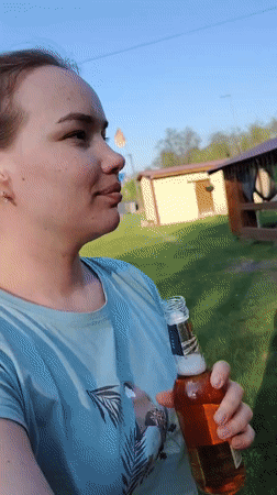 Woman enjoys beer outdoors near gazebo