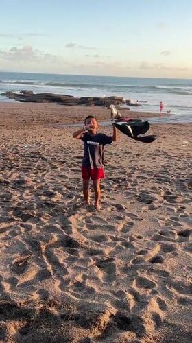 Boy flies homemade kite on Indonesian beach