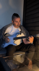 Man with mohawk plays guitar alongside Pomeranian in Oslo home